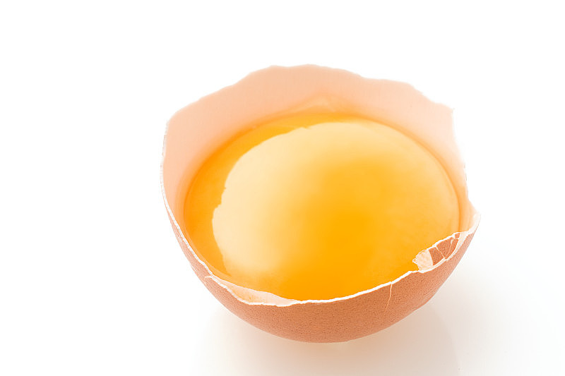 破碎的鸡蛋躺在白色的背景，有一个壳，蛋黄和溢出的蛋白质，孤立