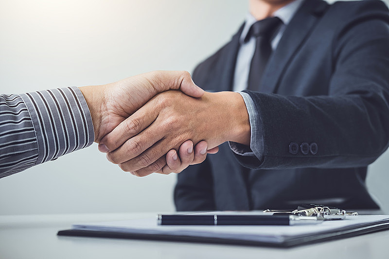 合作客户与销售人员握手后达成协议，成功签订购车贷款合同或销售新车