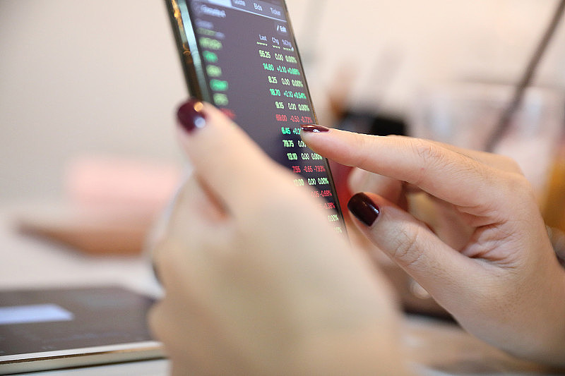 女性手用智能手机在咖啡店网上炒股，经营理念
