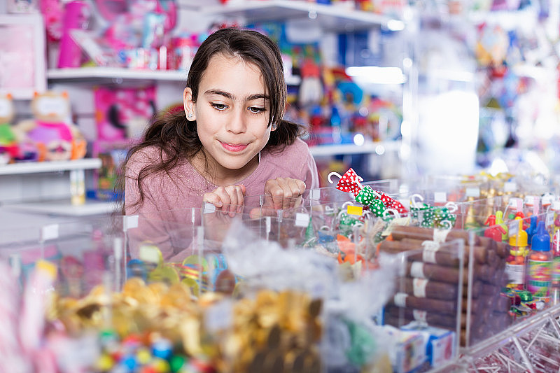 情绪化的小女孩在糖果店挑选糖果