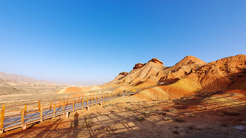 张掖国家地质公园砂岩岩层周围的步行道。中国甘肃张掖丹霞国家地质公园。以蓝天为背景的彩虹山的五彩景观。