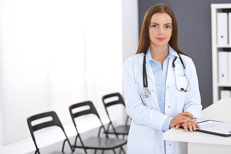 女医生在工作。女医生站在诊所或急症医院接待处附近的肖像。医疗保健理念