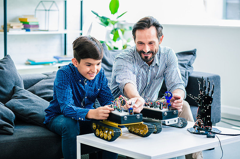 快乐的父亲和他的儿子正在制造机器人设备