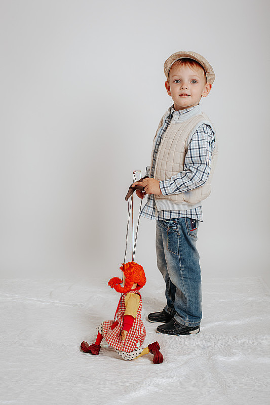 小男孩戴着帽子和一个木偶娃娃站在一起
