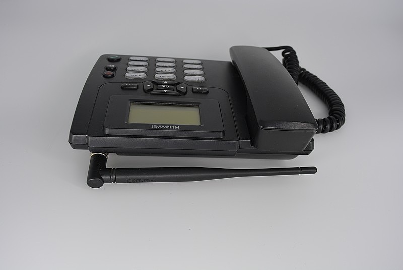 黑色固定的家用电话，带有天线，电话底座，带有白色背景屏幕的塑料办公电话。