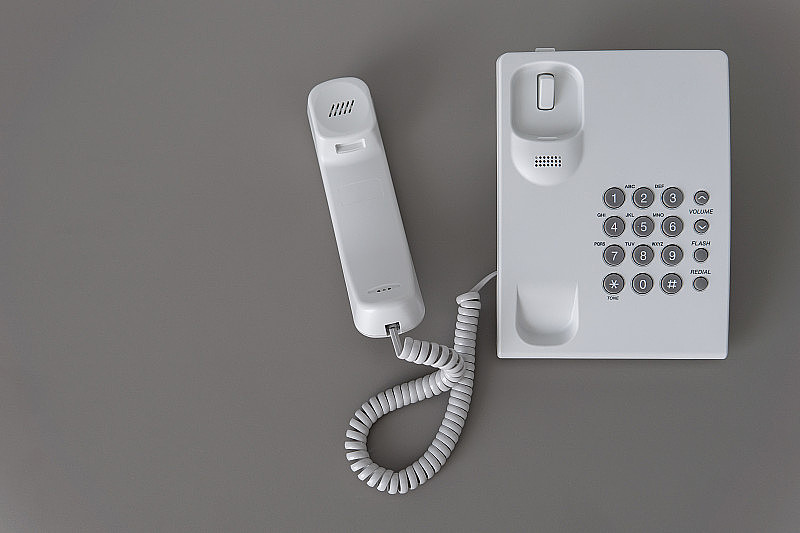 带挂钩的现代白色固定电话。技术支持的概念。不回答。特写白色电话，办公桌上的办公电话。