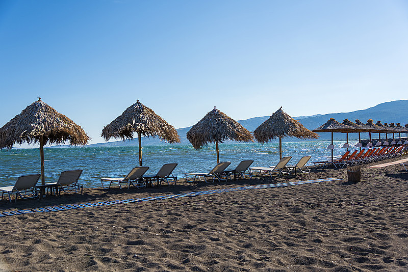 日光浴床和柳条阳伞在斯卡拉卡洛尼斯的沙滩，米蒂利尼，希腊