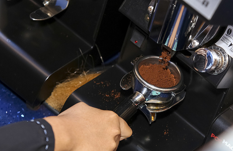现磨的咖啡豆放在咖啡研磨机的过滤网中
