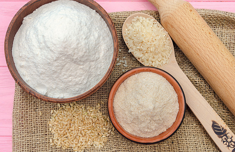 全谷米粉放在碗里。全粒米全粒米木勺糙米。健康食品的背景。