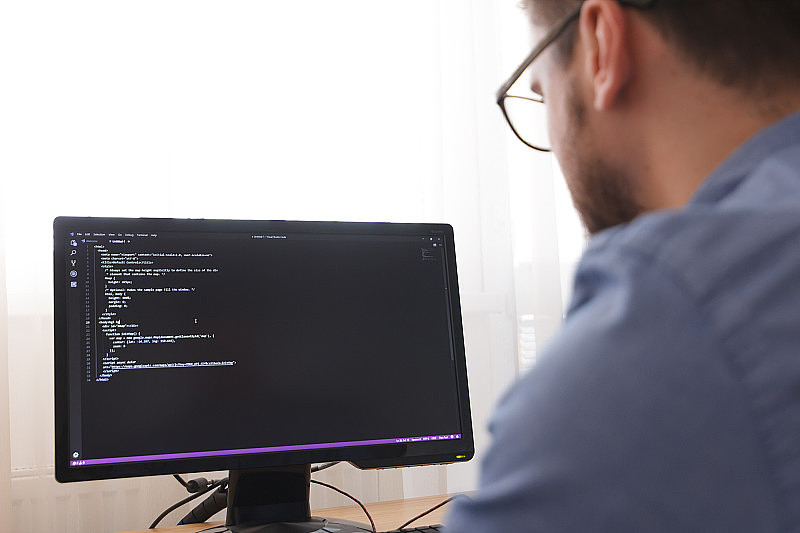 眼镜程序员输入新的HTML代码行。网站设计业务和网站开发概念。自由职业