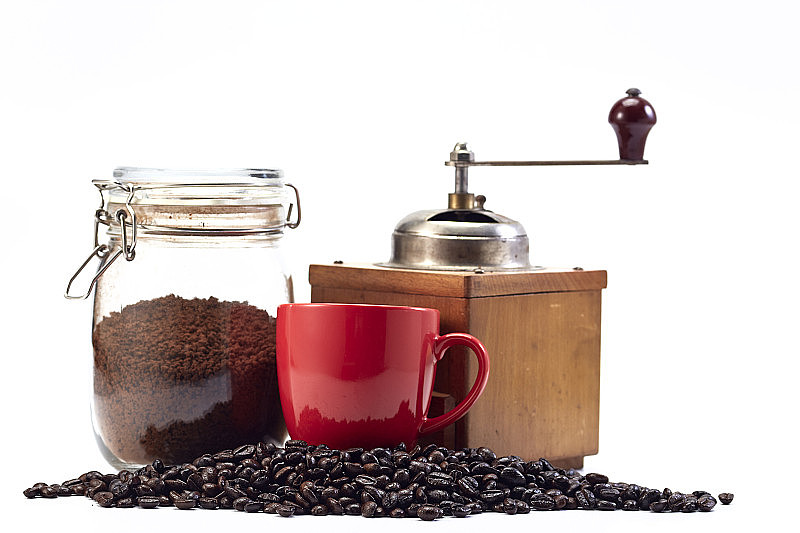 咖啡研磨机和空的红色杯与咖啡豆在白色的背景