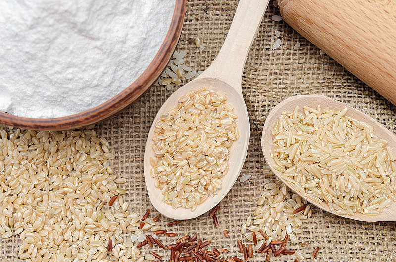 大碗米粉，糙米，木勺糙米。全粒米全粒米画布背景上的糙米和红米。健康食品的背景。