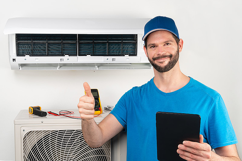 空调室内机的安装、维修、维护，由低温技术人员竖起大拇指准备去调试后，戴着蓝色衬衫棒球帽