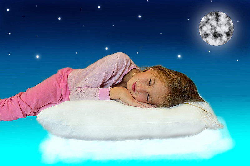 一个孩子睡在天空的云朵上的枕头上。月亮和星星在天空中闪耀。