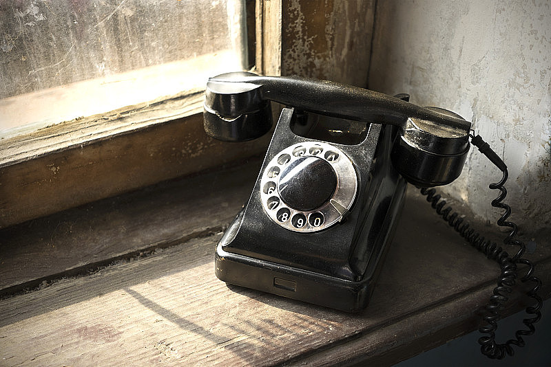 旧的黑色座机放在破旧的木窗台上。的固定电话。