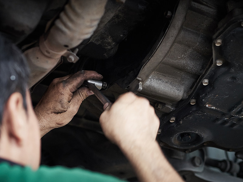 汽车机械师拧紧汽车的扭矩齿轮。修车，在车库里修车。