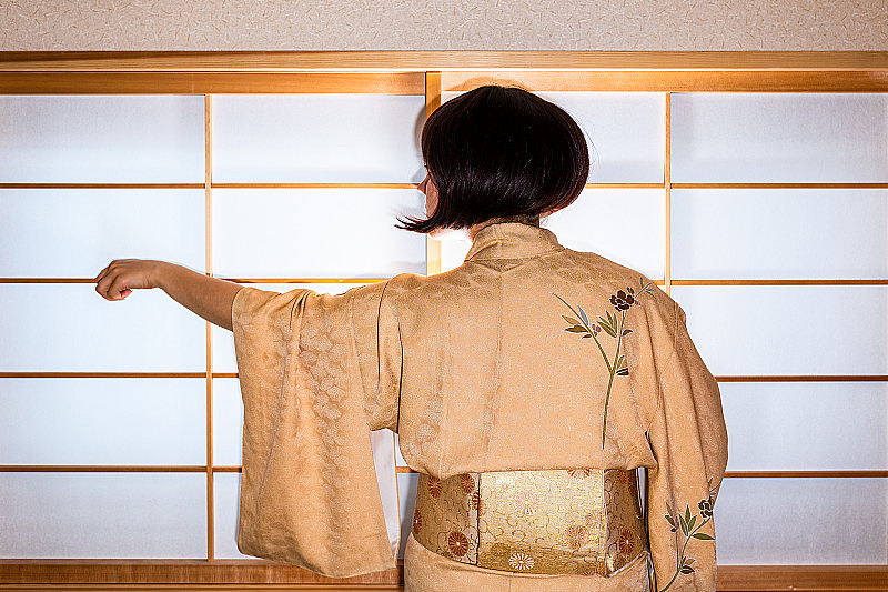 传统的日本房子推拉门窗与妇女黑头发在和服服装站与手伸出显示袖子