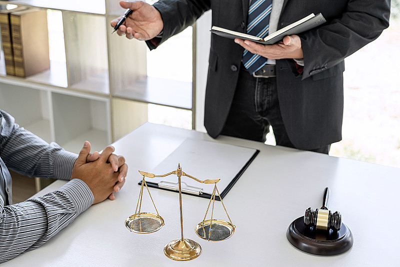 男律师或法律顾问在法庭会见客户，咨询房地产合同文件，法律及法律服务理念