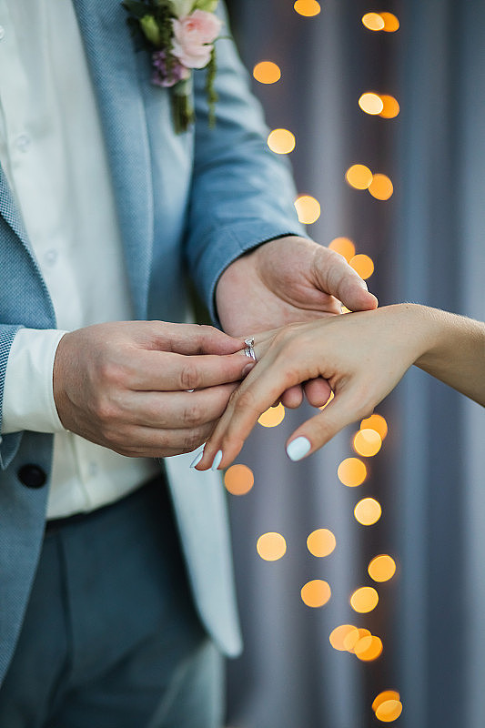 男人戴着结婚戒指在女人手上靠近。爱和承诺的象征。婚礼誓言。
