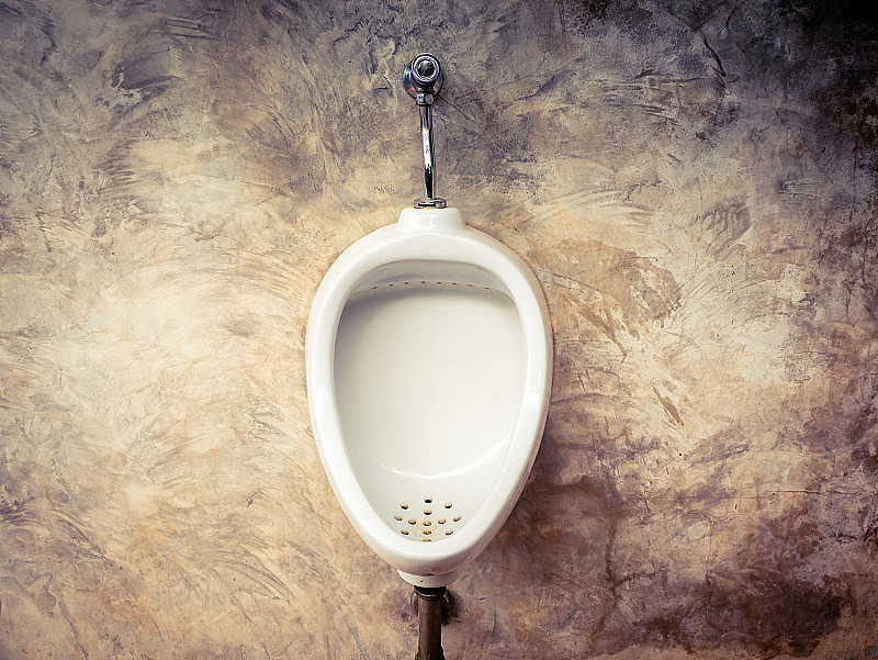 男子浴室白色小便池的特写，设计的白色陶瓷男厕小便池