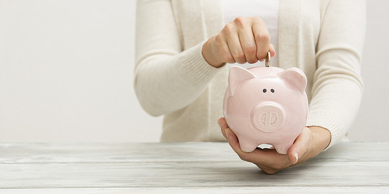 女人把手中的钱硬币放进小猪里，是为了储蓄金钱财富和理财理念。
