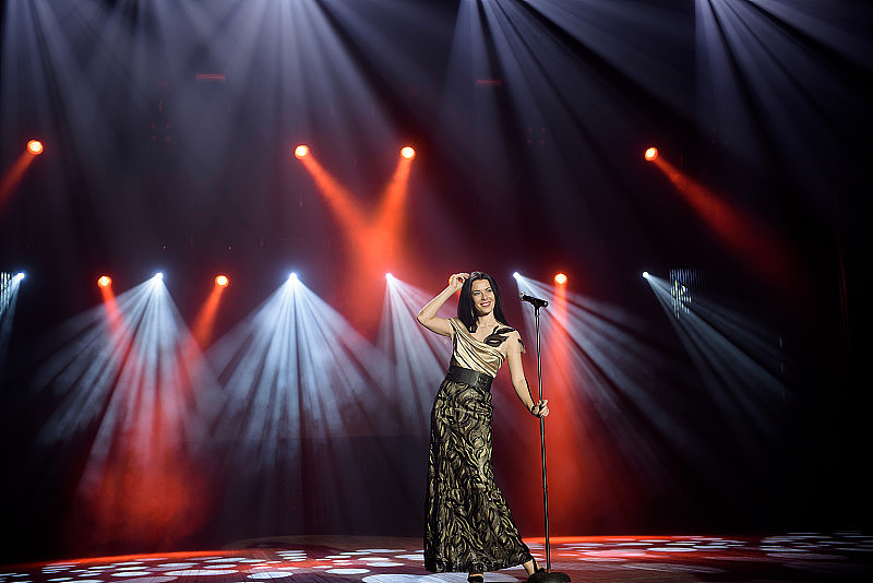 歌手在舞台上穿着礼服，在光线明亮的灯光下带着烟雾。