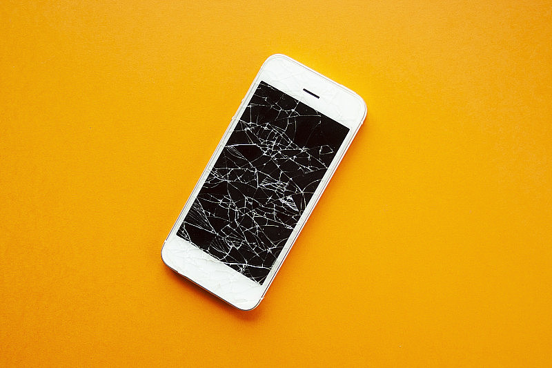 橙色背景下智能手机破碎的屏幕。手机碎玻璃，维修插图，修复电话服务。俯视图