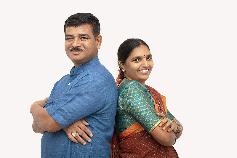 幸福的印度夫妇穿着传统服装，双手交叉，背靠背站在孤立的背景下——这是幸福快乐的夫妻关系的概念。