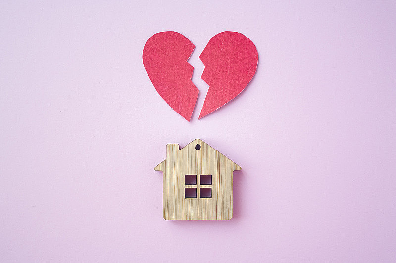离婚，财产分割，贫穷和无钱的概念。带着破碎的心的木头房子在明亮的粉红色背景上。抵押贷款、租赁、房地产经纪人