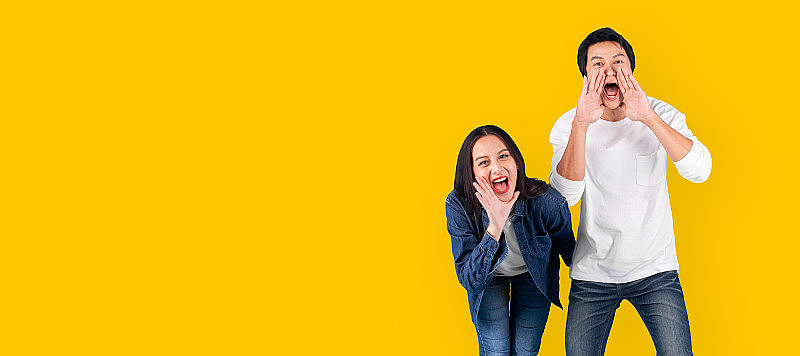 亚洲夫妇男女呼喊和宣布与大声的黄色背景与拷贝空间
