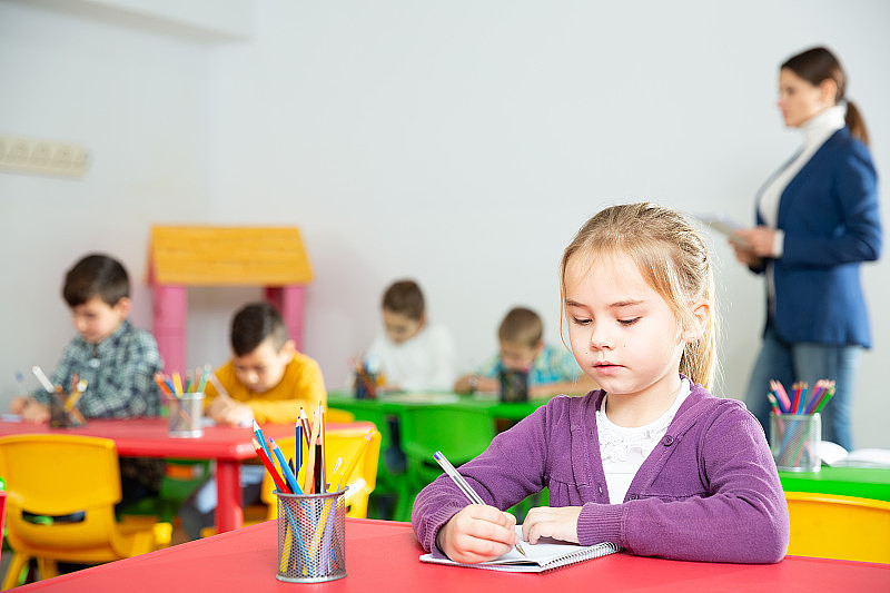 一个勤奋的小女孩拿着笔和笔记本在小学上课
