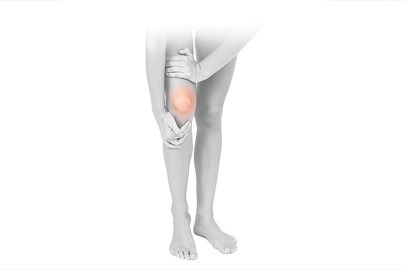 膝盖疼痛，痛点孤立在白色背景上。女人抱着她疼痛的膝盖。关节痛，医学概念，按摩，理疗，养生。