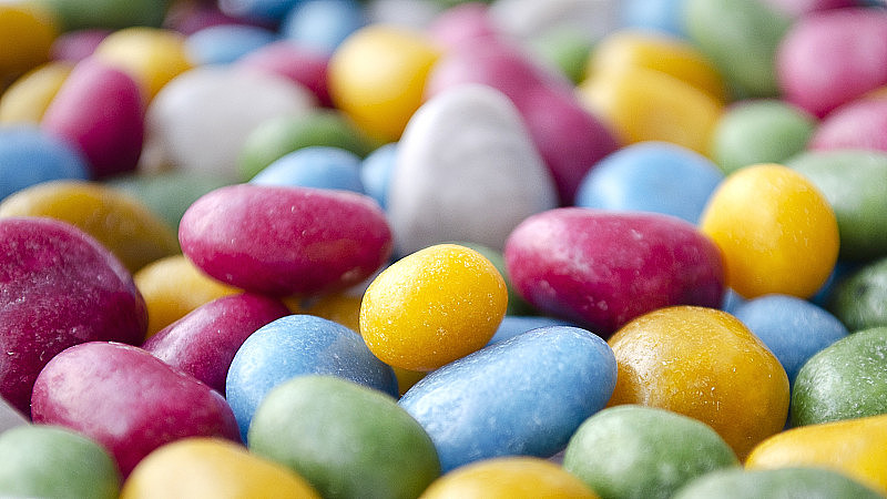 彩釉糖果。彩色糖果。模糊的照片。糖果店。背景来自多色冰糖釉。葡萄干，杏仁，涂上彩色釉。糖果的背景。