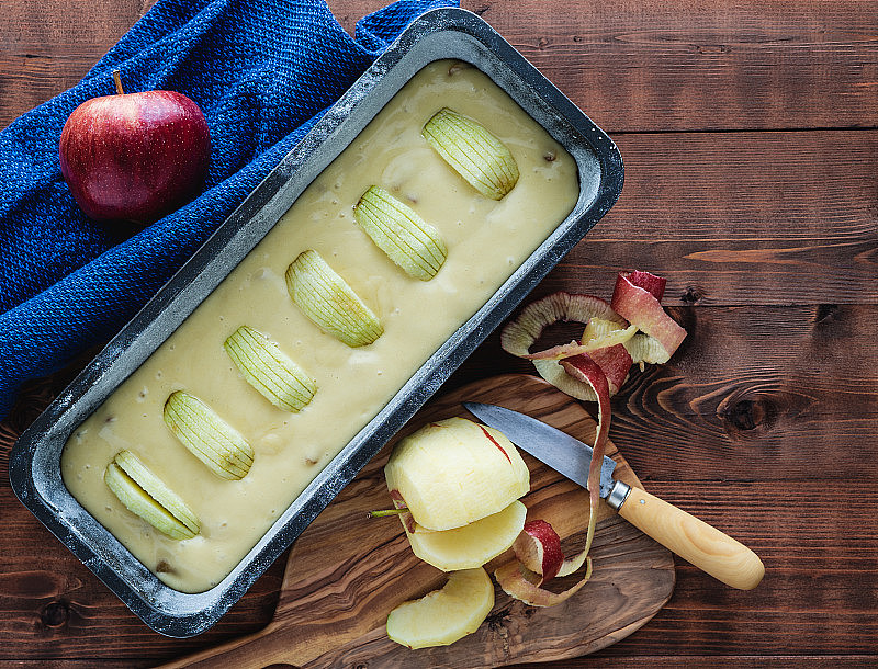 把苹果蛋糕放在深色的木质底座上，准备烘烤，上面有苹果装饰。副本的空间。糕点的概念。