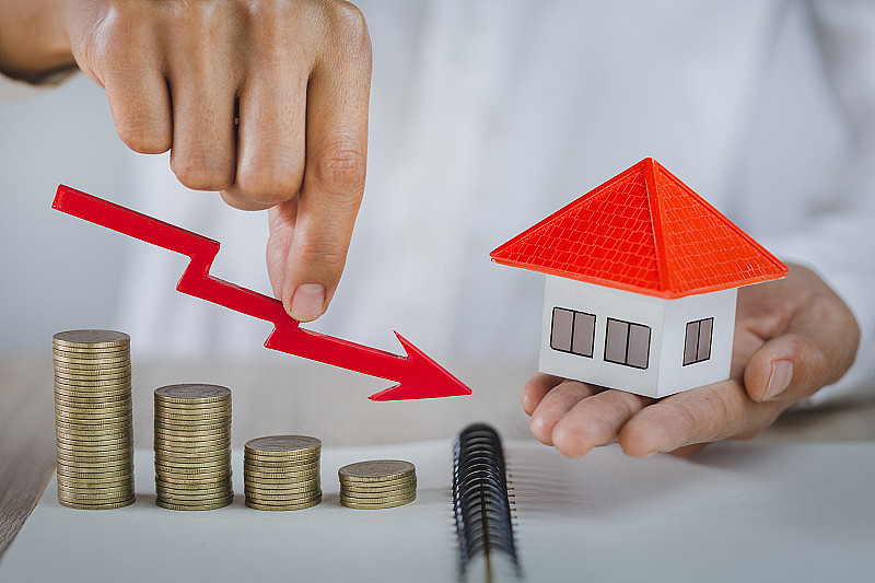 一个商人手里拿着一个红色的硬币，房地产投资和房屋抵押的金融概念，投资风险和房地产市场的不确定性，保险。