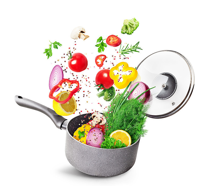 烹饪概念。蔬菜和培根落在一个孤立的平底锅上，背景是白色的。健康食品。