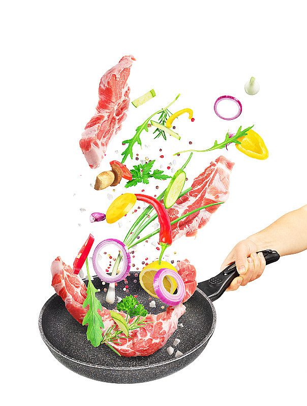 烹饪概念。蔬菜和肉类落在一个锅孤立在白色的背景。健康食品。