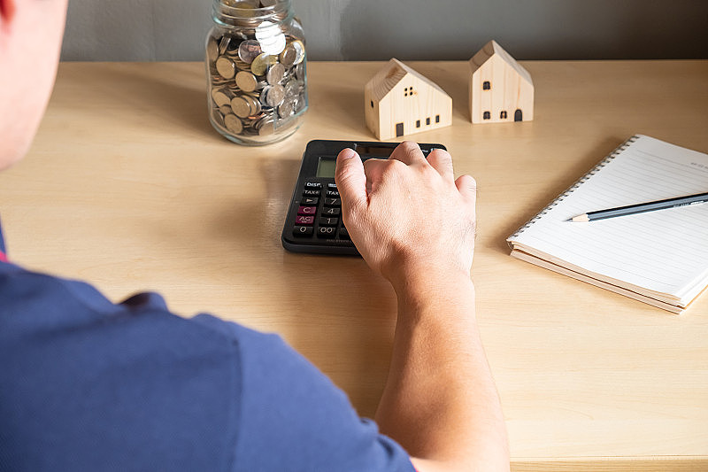 选择性聚焦于亚洲男性手中用计算器计算储蓄计划或房屋抵押贷款买房。居者有其屋概念。