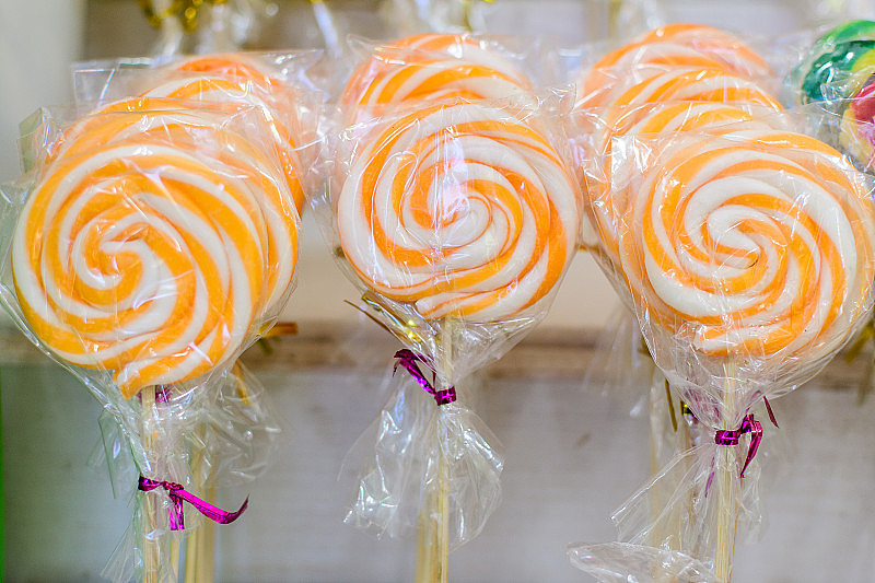 一组鲜艳的彩色糖棒棒糖在糖果店出售，在个别的塑料包装，选择性的焦点