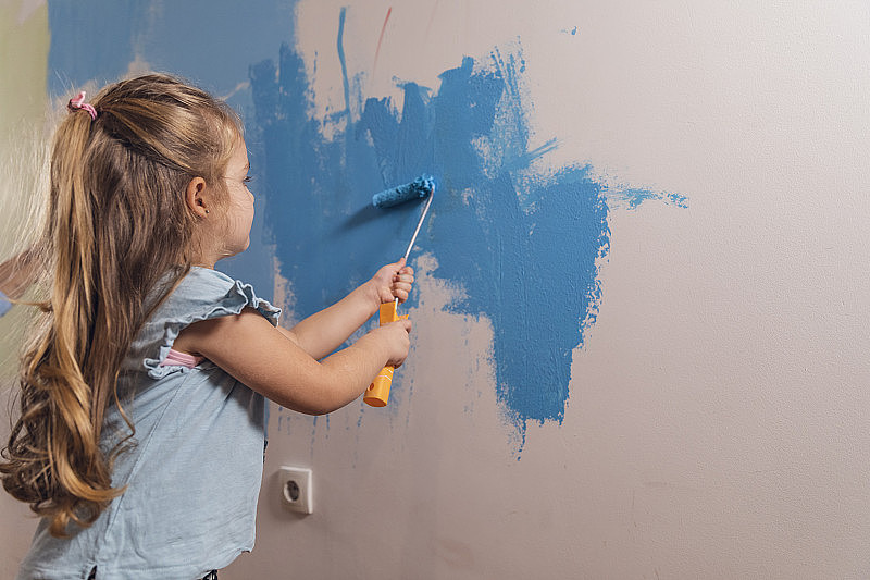 勤奋的四岁女孩把墙壁涂成蓝色
