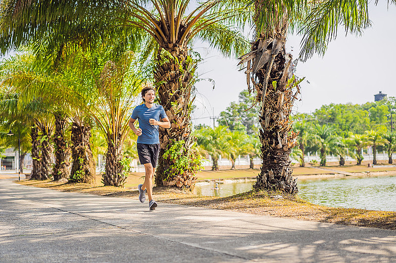 跑步运动员在热带公园跑步。男人健身日出慢跑健身养生理念