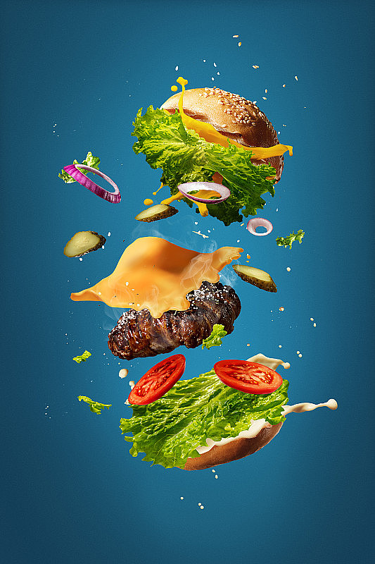 在蓝色的演播室背景下，汉堡包和飞行的配料。快餐，烹饪概念。