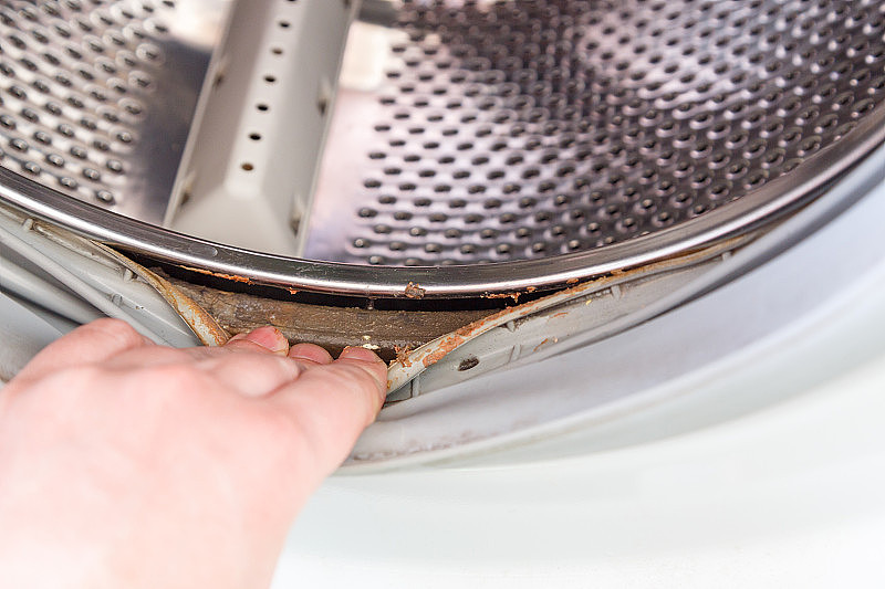手伸出洗衣机滚筒的橡皮筋，下面有一层污垢