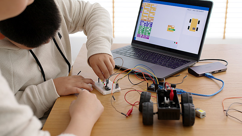 年轻的亚洲学生在家与父母远程学习编码机器人汽车和电子板电缆在STEM, STEAM，数学工程师科学技术计算机代码在机器人为孩子。