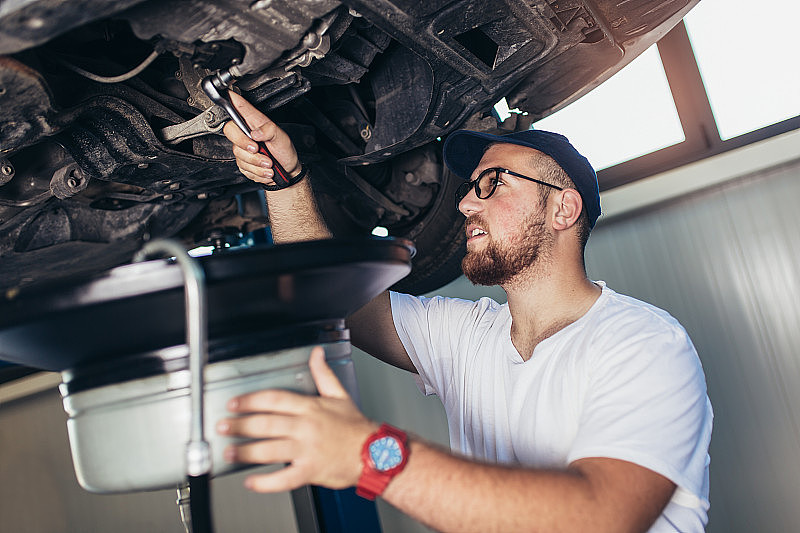 一个修理工在他的车库里修车，换油。