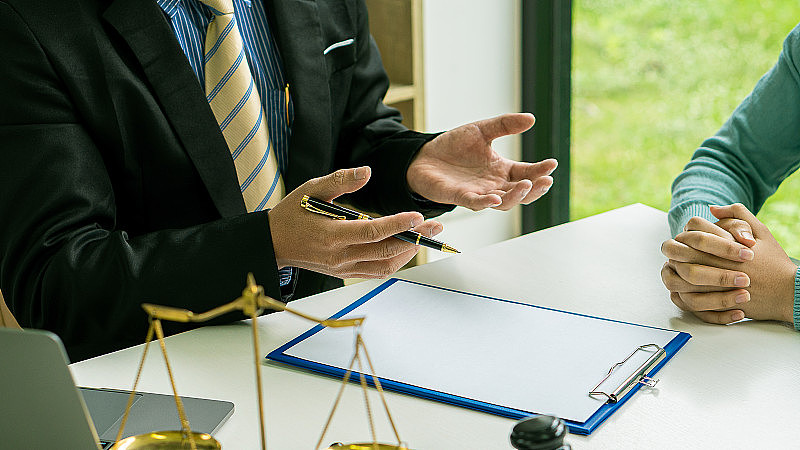 为商人、男性律师或法官提供咨询服务，与客户进行团队会议。法律服务概念，锤子和天平，合同文件，笔记本电脑在桌子上。