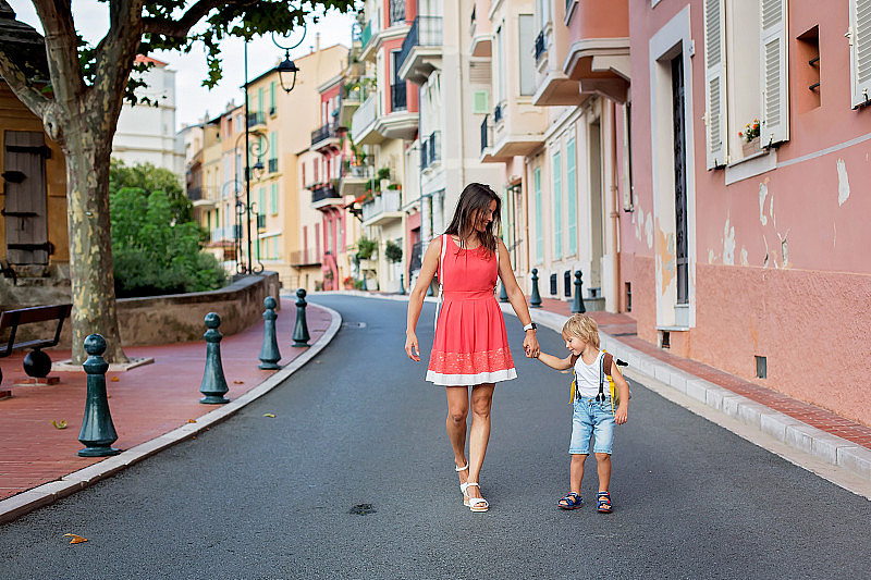 可爱的金发小孩和妈妈，蹒跚学步的男孩和父母，手牵着手走在摩纳哥的大街上