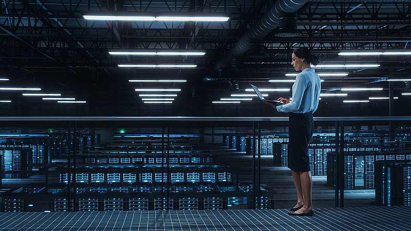 数据中心工程师使用笔记本电脑。服务器农场云计算专家设施与多种族女性系统管理员与数据保护网络为网络安全工作。