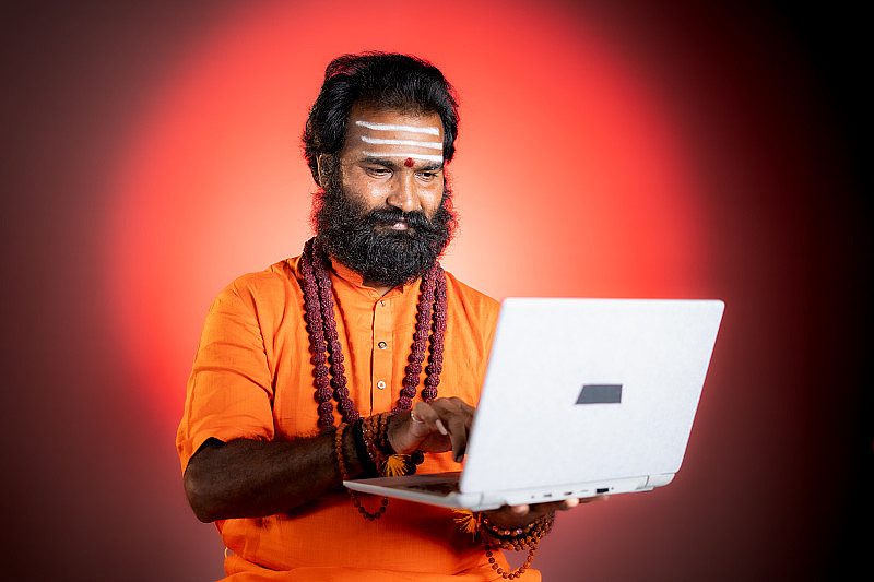 神圣的印度神人或古鲁与rudrakshi mala使用笔记本电脑-在线占星术的概念，占星术和算命使用技术和互联网