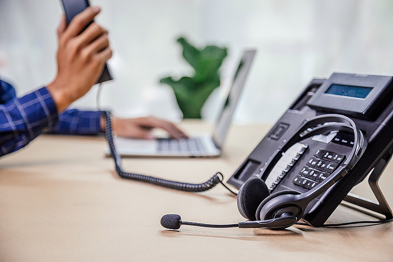 沟通支持，呼叫中心和客户服务帮助台。办公室内带VOIP耳机的电话设备。客户服务支持(呼叫中心)的概念。